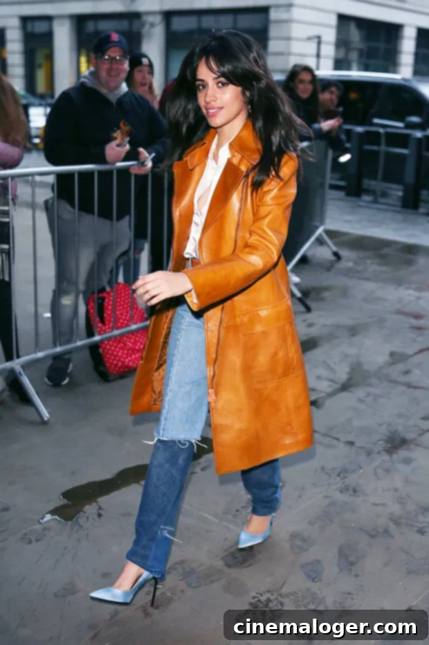 Camila Cabello wearing baby blue high heels with jeans and a camel trench coat in winter.