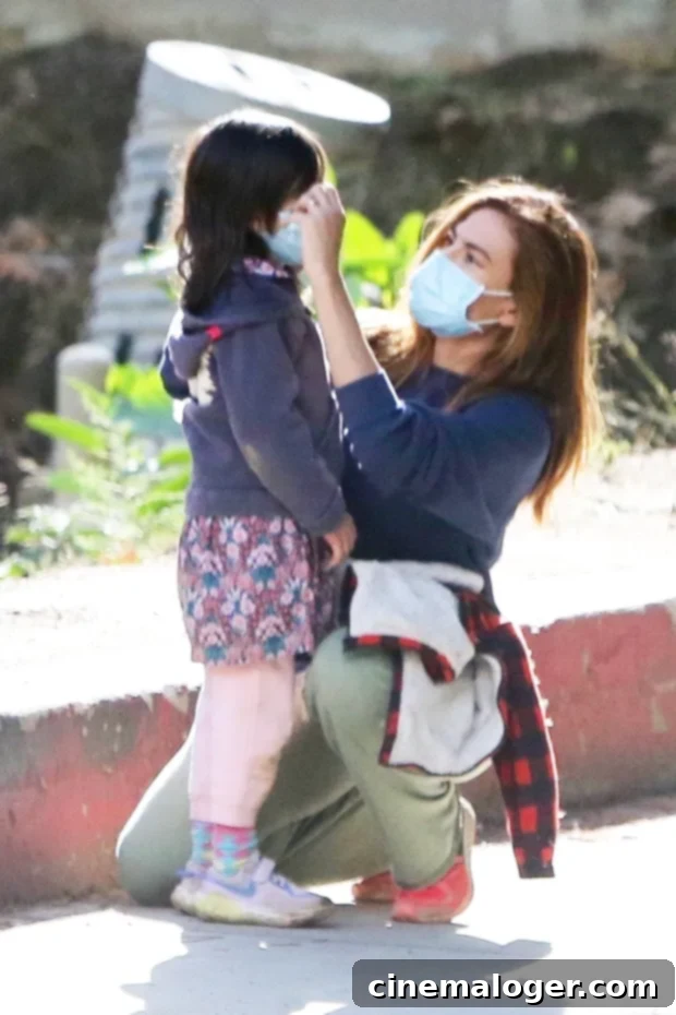 Eva Mendes's Gold Band Sparks Marriage Buzz During Rare Family Hike With Ryan Gosling 2 Eva Mendes adjusts her daughter's mask during a hike with her family in Los Feliz on January 27, 2021