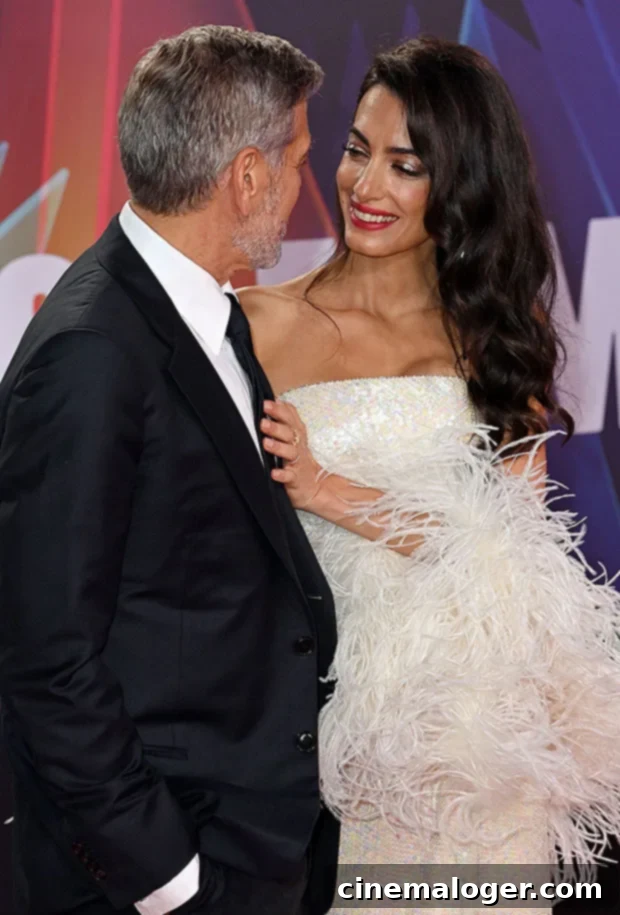 Amal Clooney Wows in Strapless Gown Alongside George at London Film Festival 3 George and Amal Clooney on the red carpet, smiling and looking at each other. Amal is in a long gown, George in a suit.