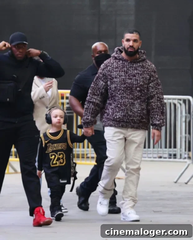 Drake's 4-Year-Old Son Adonis Wows With Incredible Basketball Talent 2 Drake and Adonis walking, Adonis wearing a Lakers jersey.