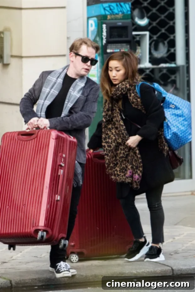 Culkin Family Rocks Matching Mohawks: Macaulay, Brenda, and Son Dakota Step Out 3 Macaulay Culkin and Brenda Song walking together while holding suitcases, perhaps after a trip.