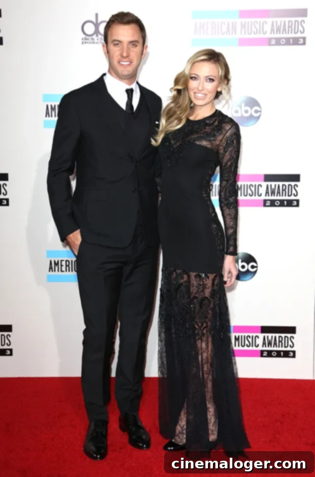 Paulina Gretzky and Dustin Johnson's Journey to Marriage: A Complete Relationship Timeline 2 Dustin Johnson and Paulina Gretzky smiling and posing at the 2013 American Music Awards, Paulina in a white dress and Dustin in a black suit.