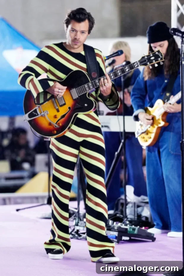 Harry Styles Takes Home VMA Album Of The Year, Apologizes For Missing The Show 3 Harry Styles performing live on stage, wearing a colorful striped outfit.
