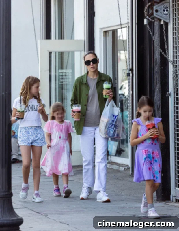 Gal Gadot & Her Girls Beat the Heat with Iced Drinks 2 Gal Gadot and her daughters Maya and Alma enjoying a casual outing in Los Angeles, October 2022. They are seen walking with a third child and holding cold beverages, showcasing a rare public moment of the family.