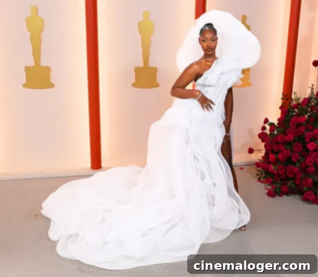 Tems' Controversial Oscars Gown Creates Social Media Firestorm 3 Tems posing elegantly in her white Lever Couture Oscars dress at home, showcasing its voluminous design.
