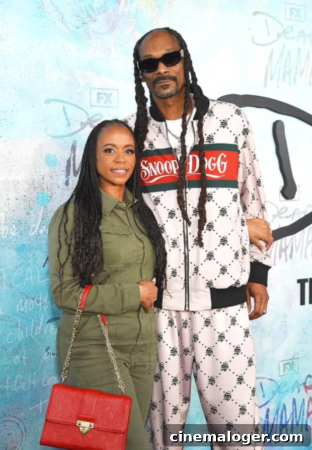 Snoop Dogg's Premiere Night A Family Portrait 3 Cordé Broadus in pink and yellow, and Cordell Broadus in a varsity jacket, pose confidently on the red carpet at the 'Dear Mama' premiere.